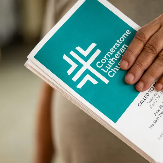 Close-up of a hand holding a Cornerstone Lutheran Church bulletin.