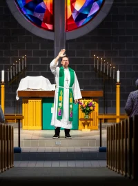 A pastor raising his hand in blessing at the altar during a service.