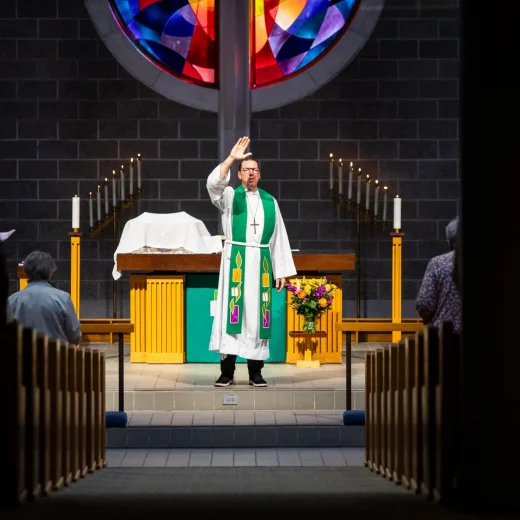 A pastor raising his hand in blessing at the altar during a service.