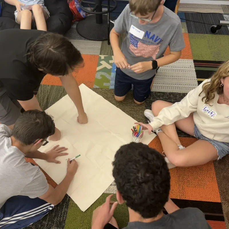 A group of teens creatively collaborating on an indoor project.